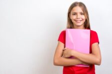 smiling schoolgirl carrying copybook